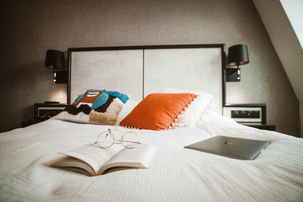 an open book and glasses on a bed with aaptop at La Maison Montparnasse in Paris