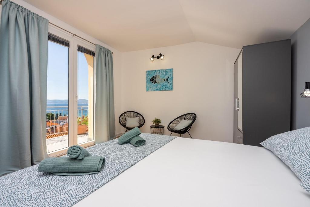 a bedroom with a bed with two chairs and a window at Apartments Kala in Crikvenica