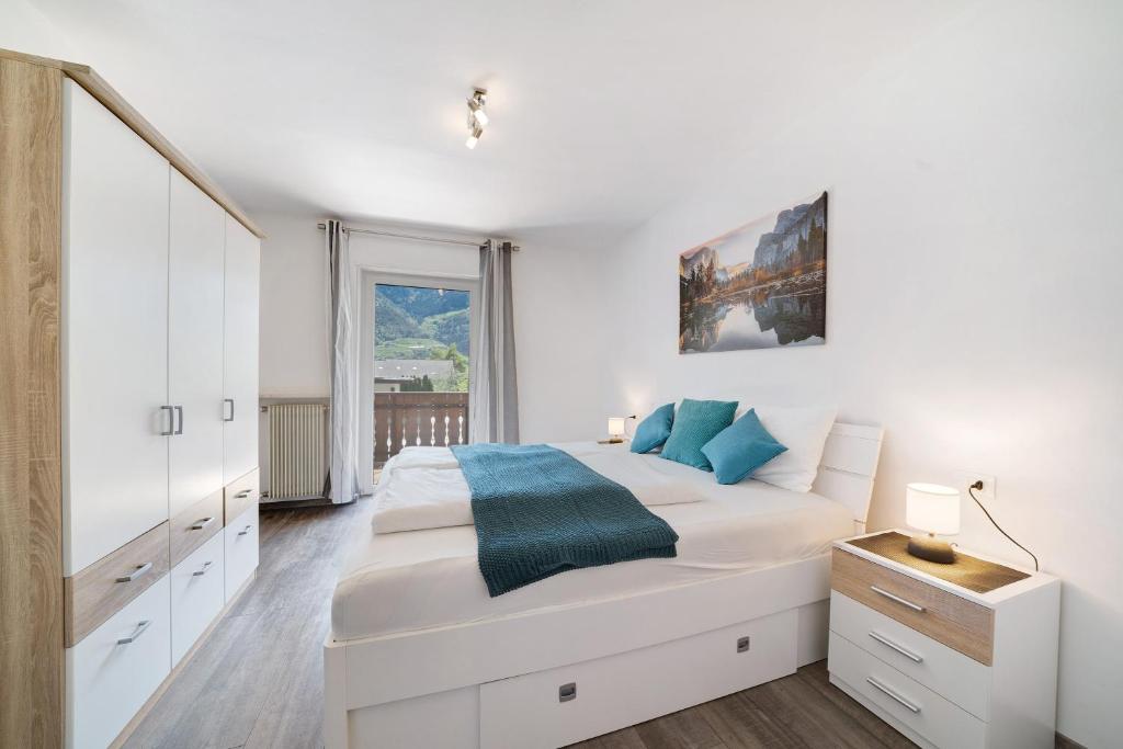 a white bedroom with a large bed and a window at Haus Tanja Apartment 2 in Parcines