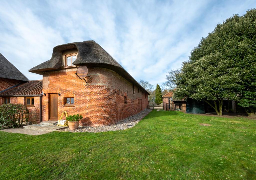 uma casa de tijolos com telhado de palha num quintal em Bluddles Dairy em Somerton