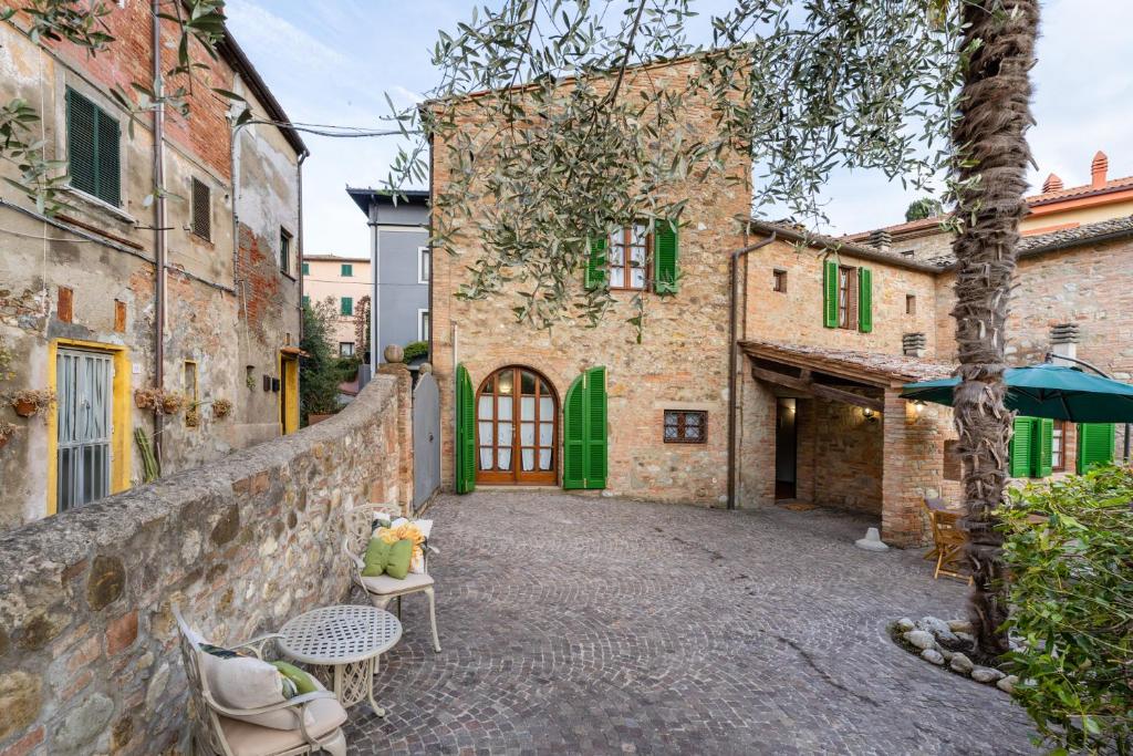 Une allée dans un ancien bâtiment en pierre avec des tables et des chaises dans l'établissement Casa di Alice nel Borgo, à Lajatico