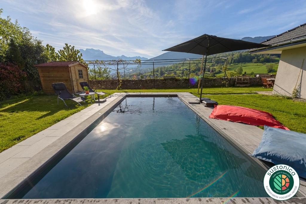 - une piscine avec un parasol dans la cour dans l'établissement Charmante maison avec Vue LAC et Montagnes - PISCINE privative - LLA Selections by Location lac Annecy, à Saint-Jorioz