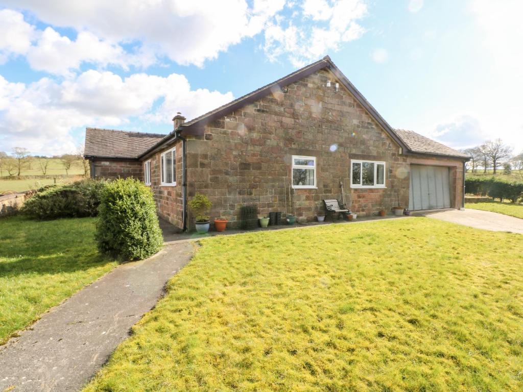 a brick house with a large yard in front of it at Hawksbridge Bungalow in Macclesfield