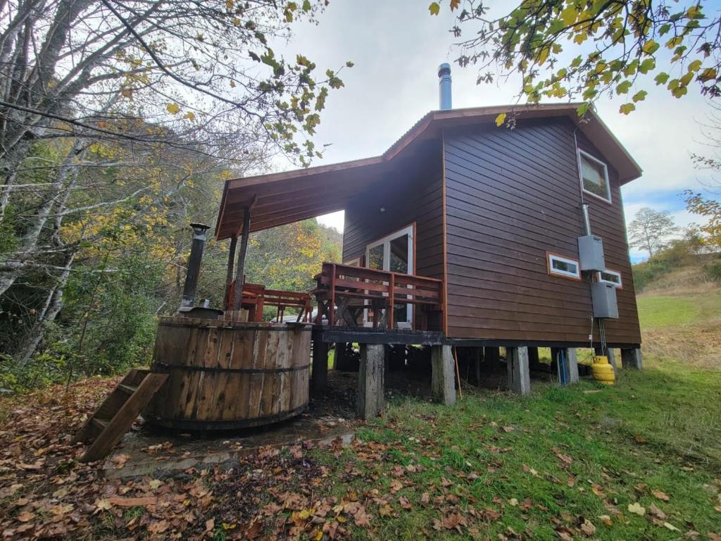 a log cabin in the woods with a barrel at Entre Pampa y Bosque in Villarrica