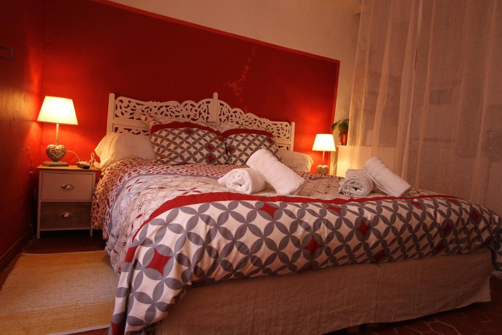 - une chambre avec un grand lit et un mur rouge dans l'établissement Studio le coquelicot, à Cotignac