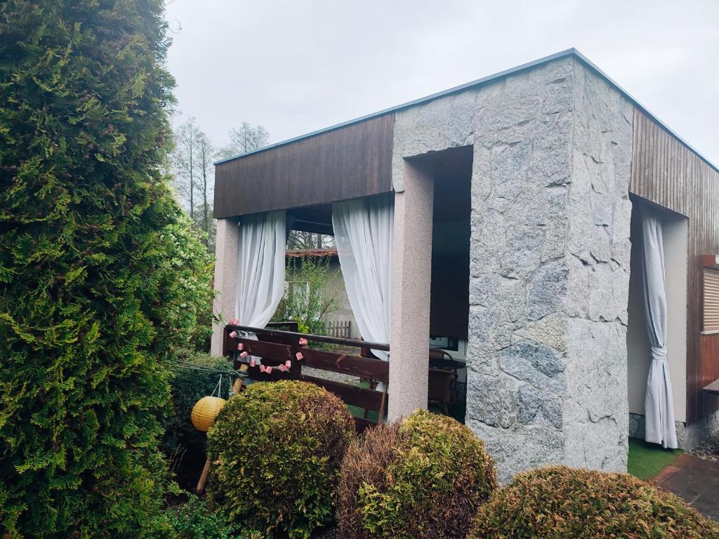 un edificio de piedra con un banco en un jardín en Domek letniskowy w Miliczu, en Milicz
