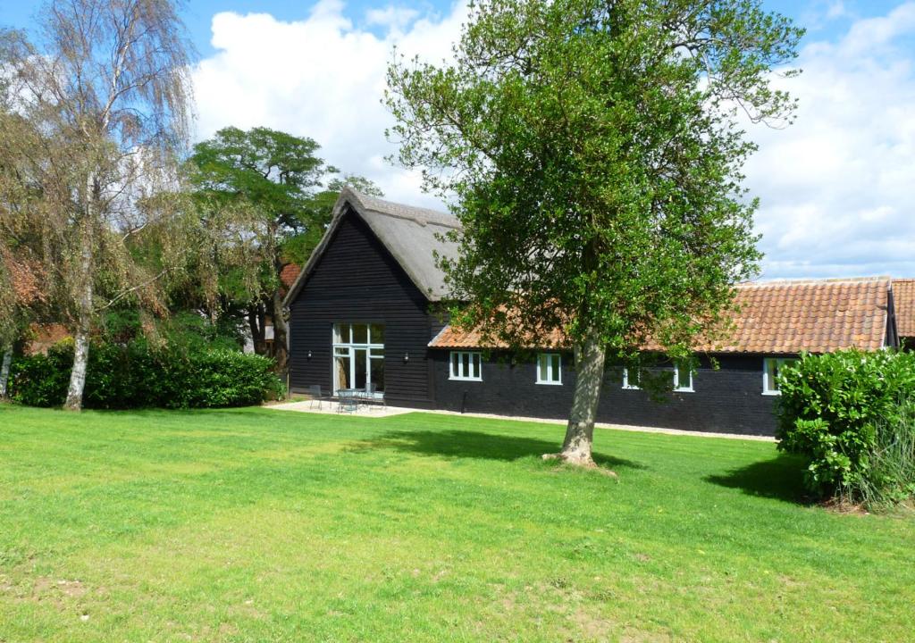 une maison noire avec un arbre dans la cour dans l'établissement Burtons Farm Barn, 