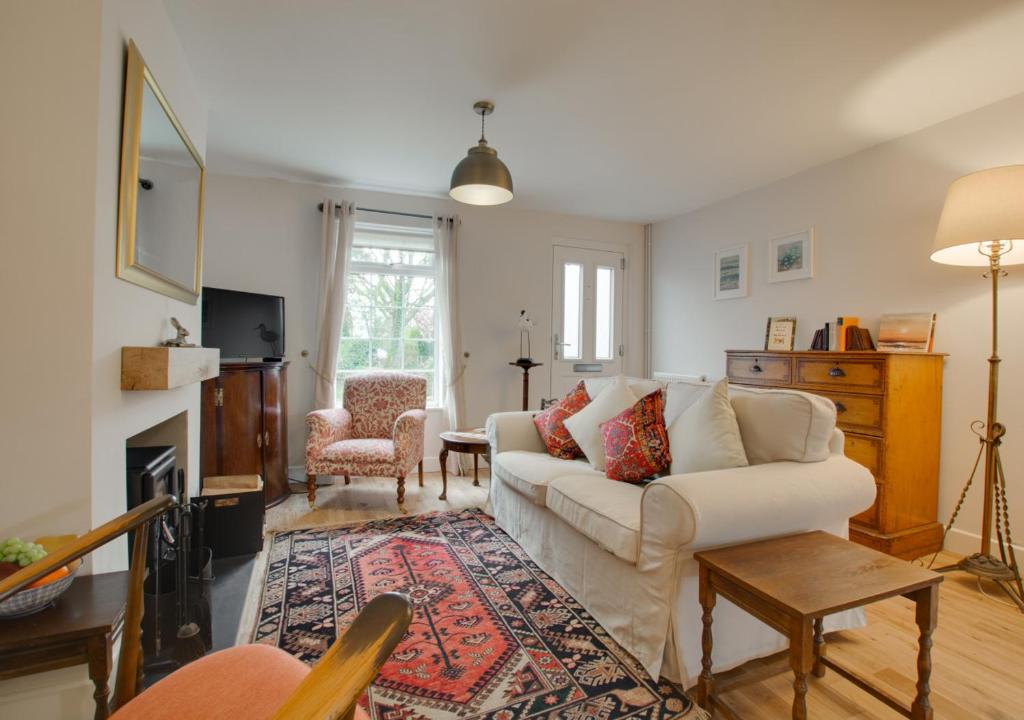 a living room with a white couch and a table at Brook Cottage in Dersingham