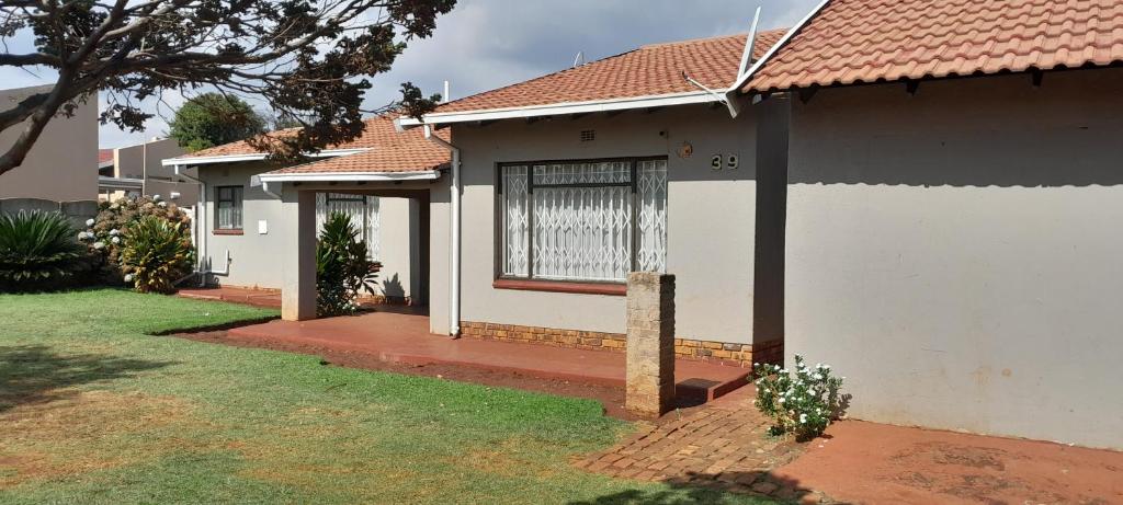 a white house with a window and a yard at Dawn Park Guest House in Boksburg