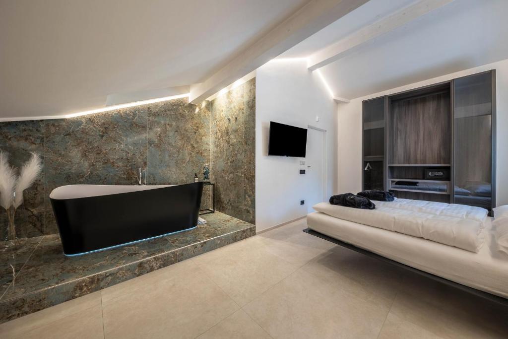 a bathroom with a tub and a bed and a tv at App 302 Palazzo Cavour in Bolzano