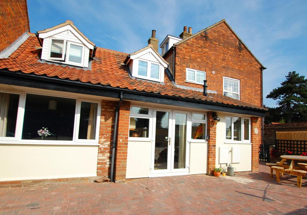 Casa de ladrillo con puertas blancas y patio en Corner Cottage, en Wells-next-the-Sea
