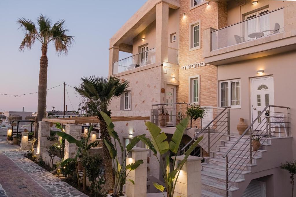 a building with a palm tree next to a street at Miramare Apartments in Platanias