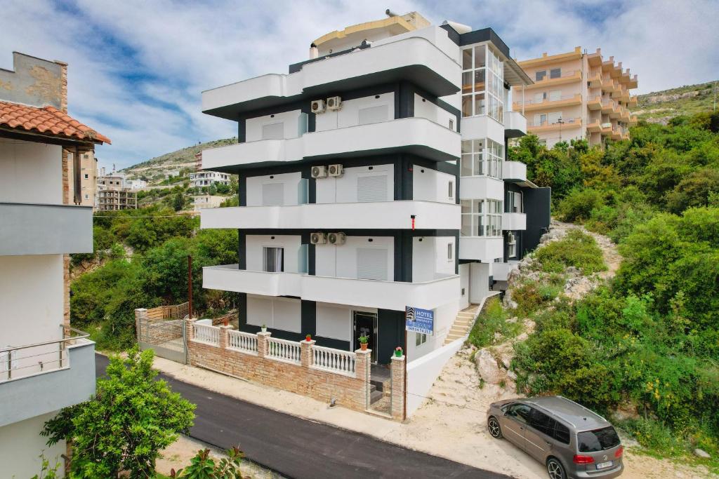 een gebouw waar een auto voor geparkeerd staat bij Apartments & Hotel Eleanna in Sarandë