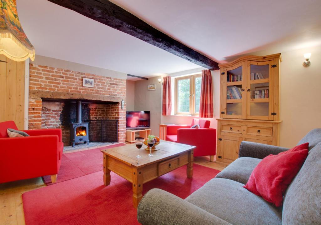 a living room with a couch and a fireplace at East Cottage in Corpusty