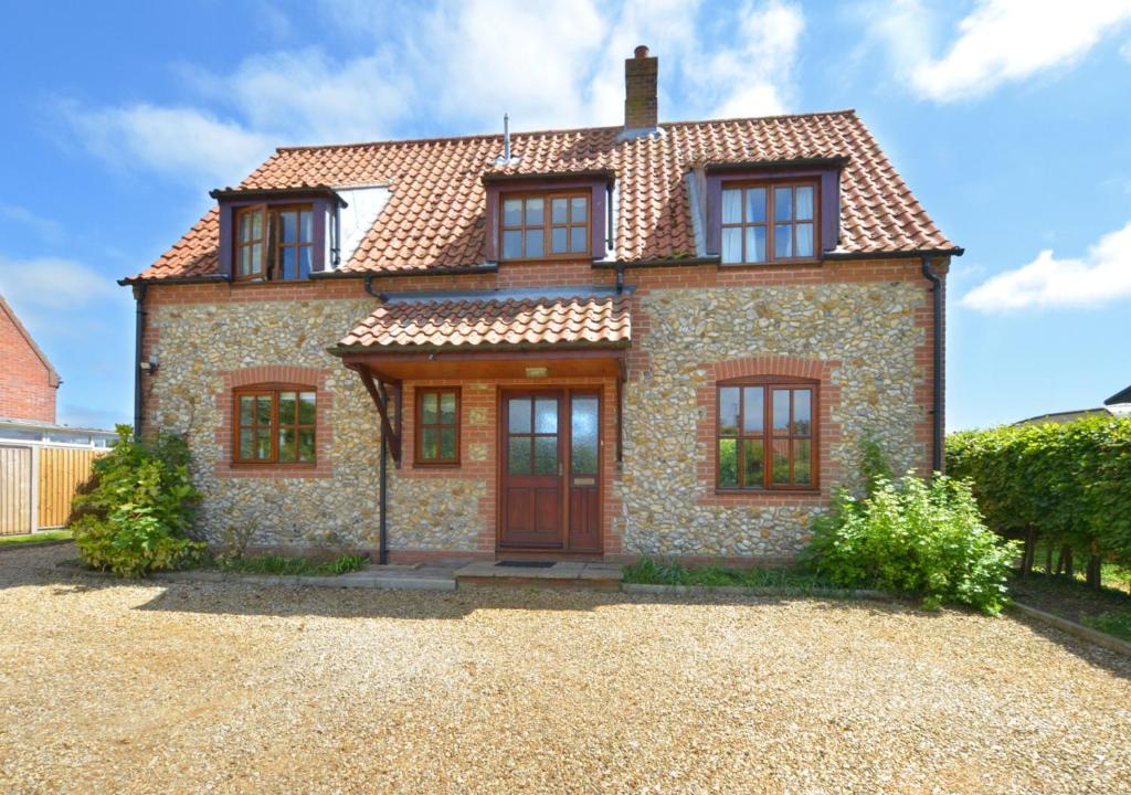 una grande casa in pietra con una porta rossa di Ebenezer Cottage a Burnham Market