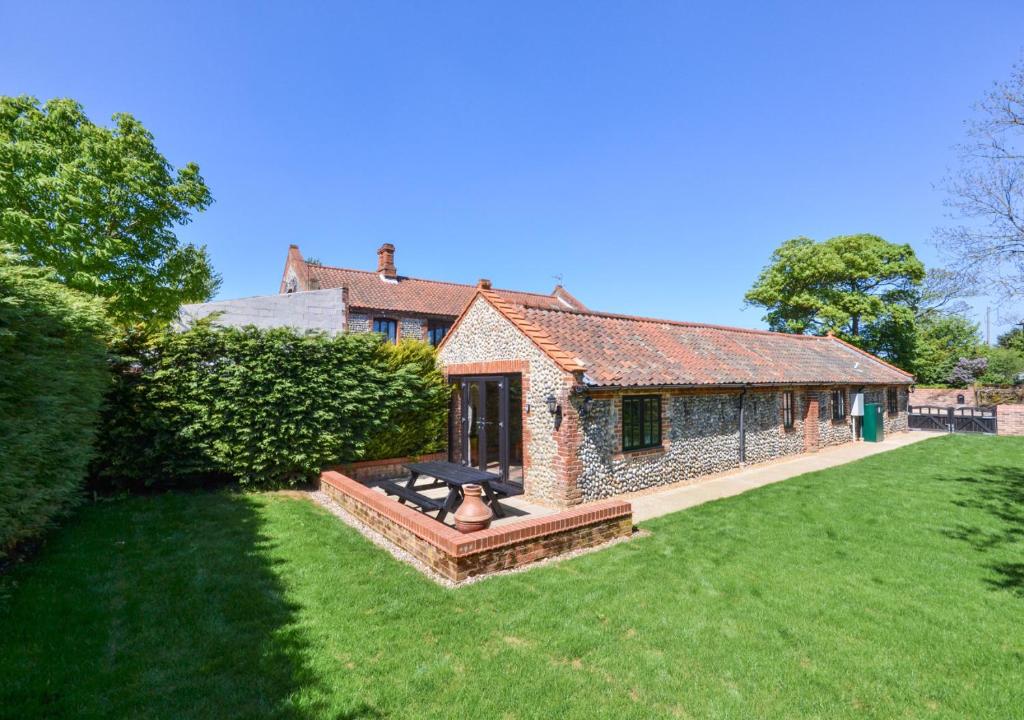 a brick house with a fire pit in a yard at Farm Cottage in Sidestrand