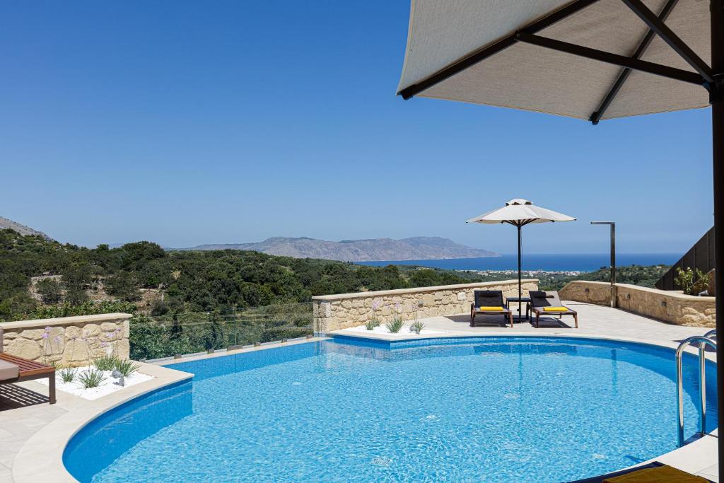 a swimming pool with two chairs and an umbrella at Villa Vardina in Chania Town