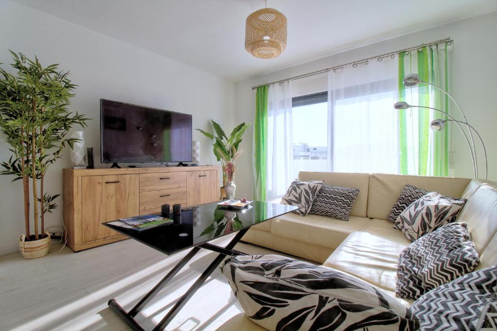 uma sala de estar com um sofá e uma televisão em Center location, AC, swimming pool, and parking em Olhão