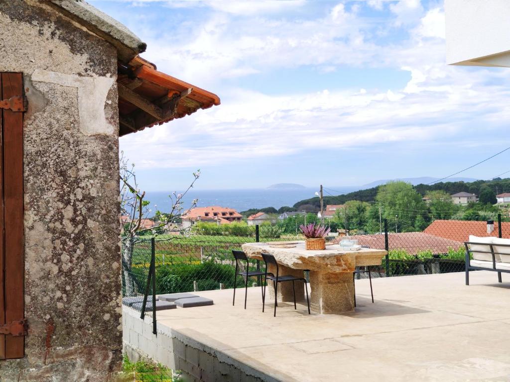 eine Terrasse mit einem Tisch und Stühlen sowie Aussicht in der Unterkunft Desconectaengalicia Casa A de Lola in Sanxenxo