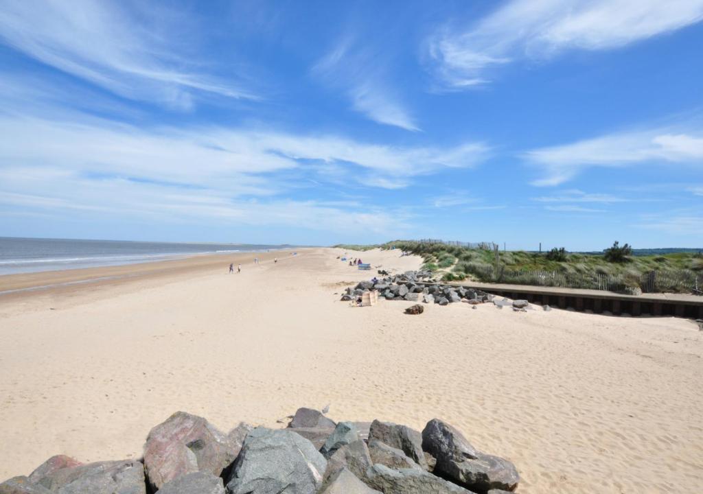 una playa con un grupo de personas caminando en ella en Hillview, en Brancaster