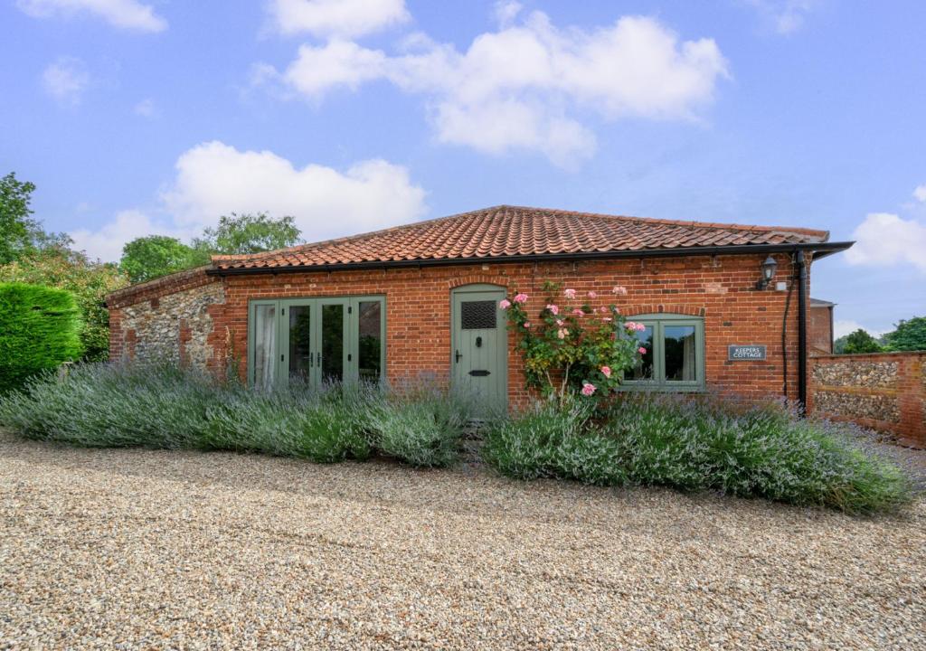 a brick house with flowers in front of it at Keepers Cottage in East Dereham