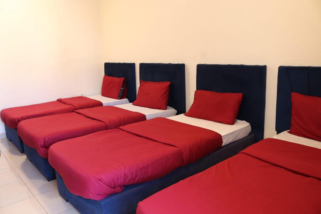4 Betten mit roten Kissen in einem Zimmer in der Unterkunft Future 2 Hotel Apartments in Aqaba