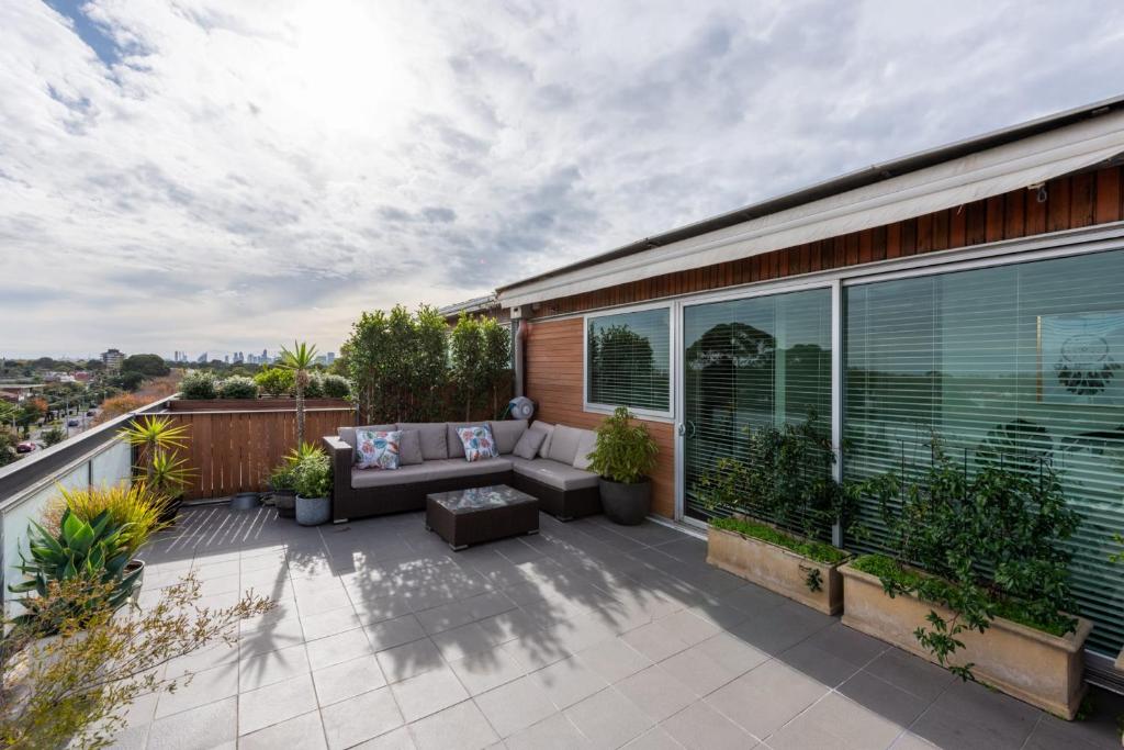 patio con sofá y sillas en el balcón en Beautiful 1-Bed in St Kilda w Parking & Terrace, en Melbourne