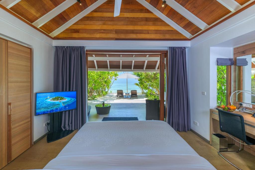 a bedroom with a large bed and a tv at Kandolhu Maldives in Himandhoo 