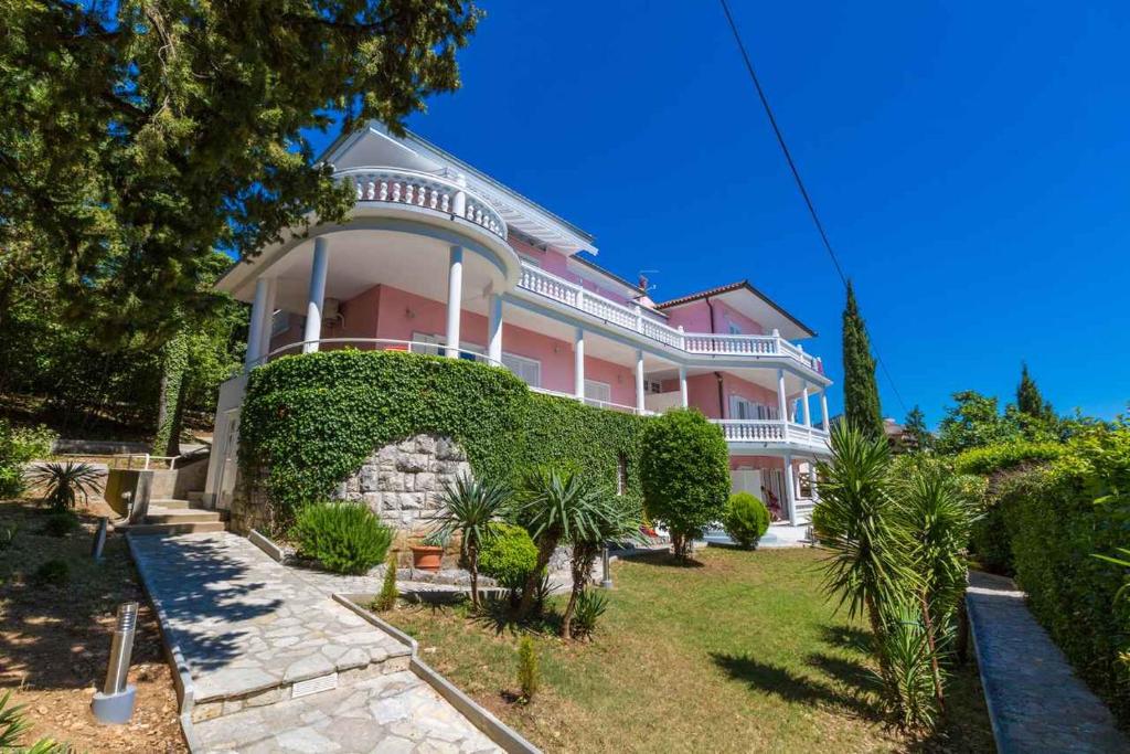 a large pink house with a green hedge at Two-Bedroom Apartment in Crikvenica VI in Sopaljska