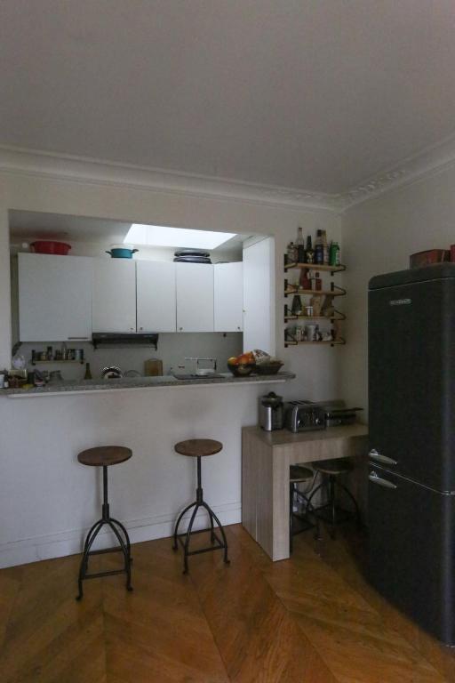 eine Küche mit zwei Barhockern und einem Kühlschrank in der Unterkunft Comfortable and spacious apartment in Paris 3rd in Paris