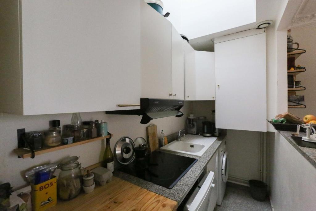 eine kleine Küche mit weißen Schränken und einem Waschbecken in der Unterkunft Comfortable and spacious apartment in Paris 3rd in Paris