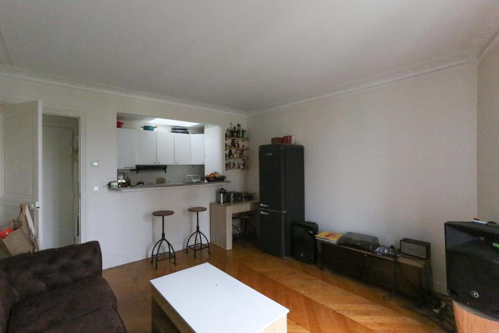 ein Wohnzimmer mit einem Sofa und einer Küche in der Unterkunft Comfortable and spacious apartment in Paris 3rd in Paris