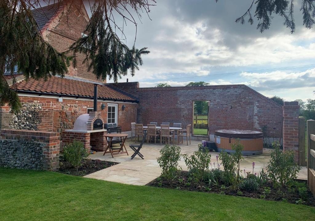 a brick house with a patio and a grill at Manor Farm in Brampton
