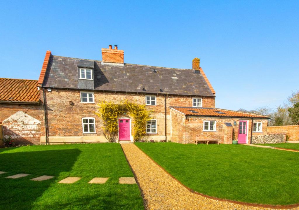uma grande casa de tijolos com uma porta vermelha e um jardim de relva em Manor Farm em Brampton