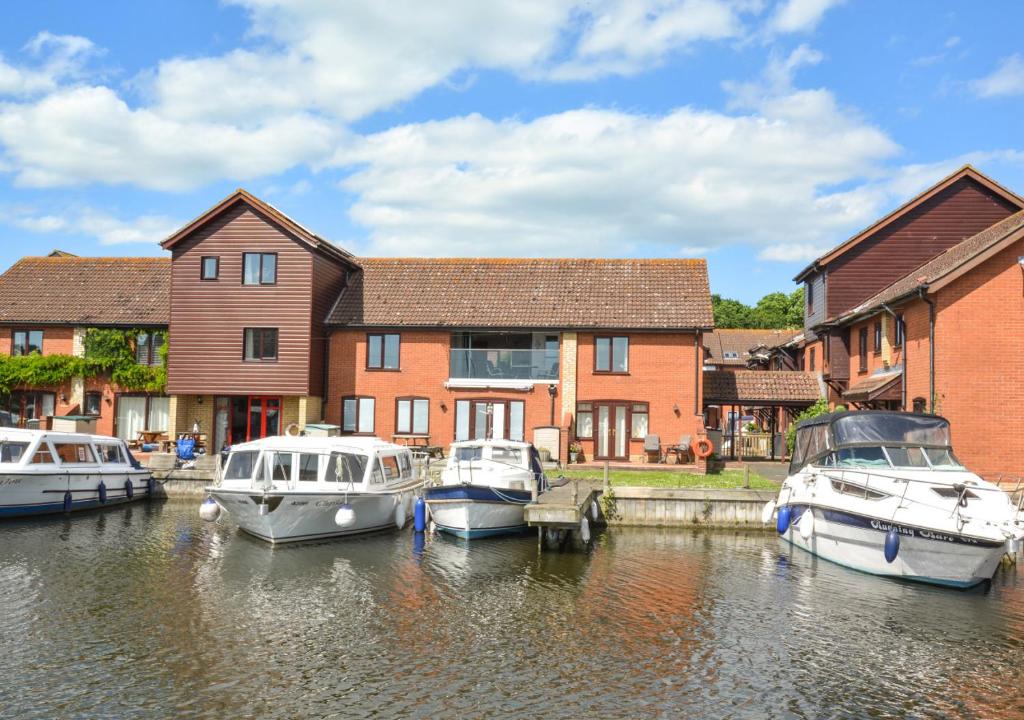 a group of boats docked in the water next to houses at Marina Outlook in Horning