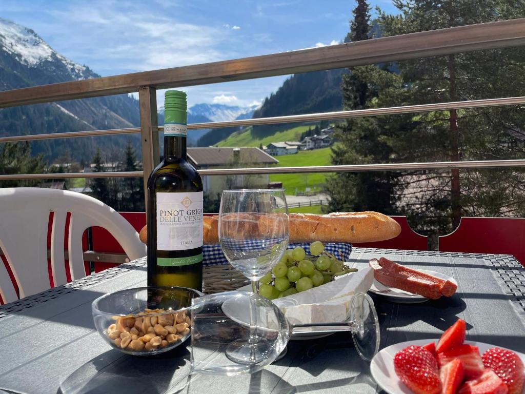 una mesa con una botella de vino y un plato de fruta en Appartement 412 Kunners Oostenrijk en Mittelberg