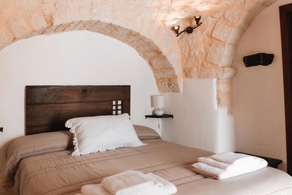 - une chambre avec un lit et un mur en pierre dans l'établissement Il Trullo Nascosto, à Alberobello