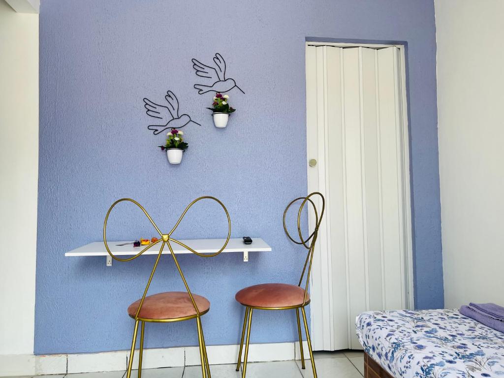 La casita lilás في بيبيريبي: غرفة نوم مع كرسيين وطاولة مع عصفورين على الحائط