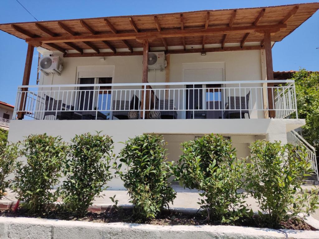 une maison avec un balcon et des arbres devant elle dans l'établissement Elina House and Garden, à Nikiti