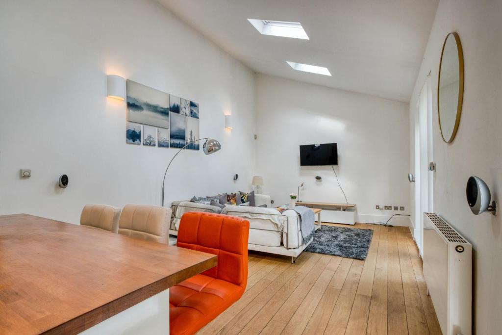 a living room with an orange chair and a table at Stunning Award Winning Barn Conversion- 2 Bedroom in London