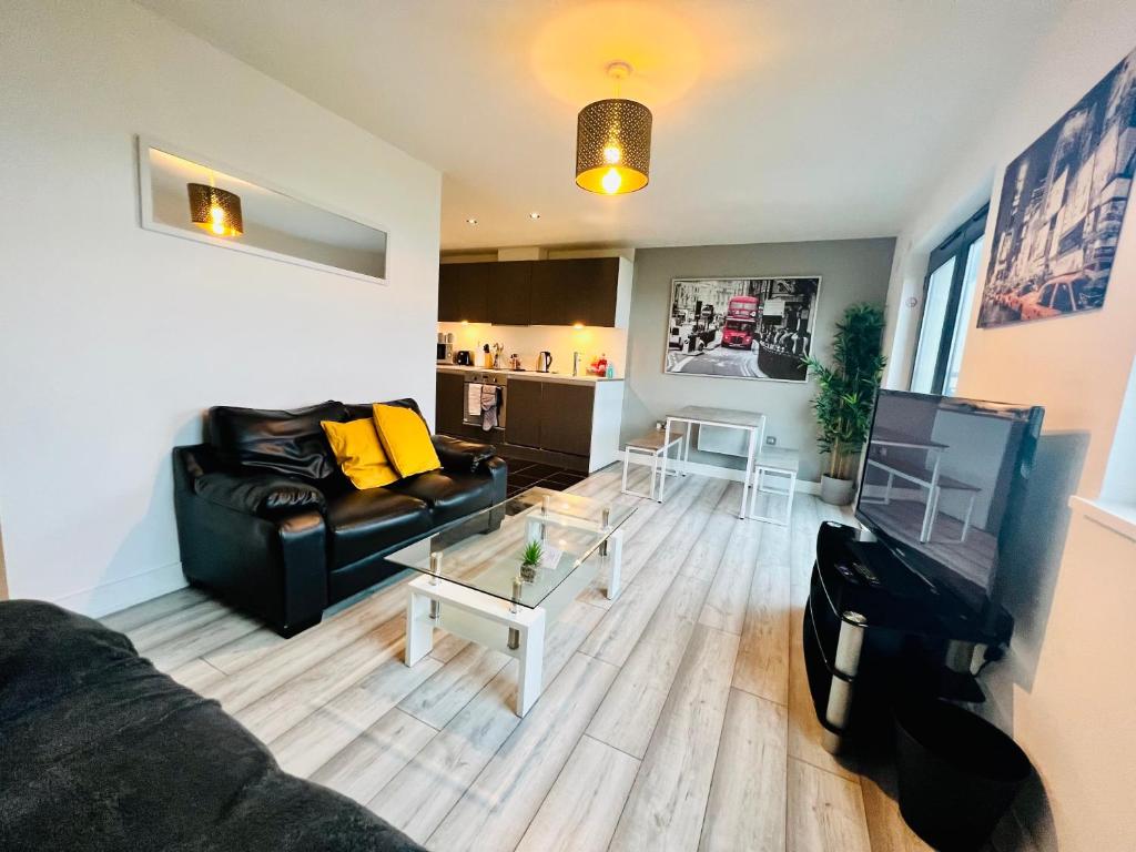 uma sala de estar com um sofá preto e uma mesa em Lush Cardiff Bay Apartment with Secure Parking and Fast Wifi em Cardiff