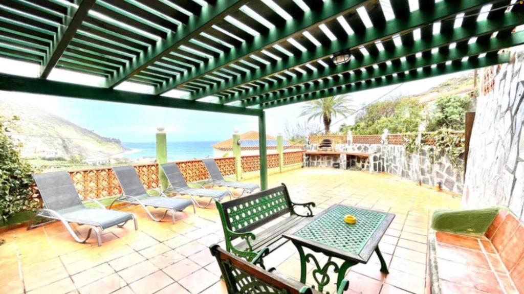 a patio with a table and chairs and the ocean at Casa Rural Ondina in Hermigua