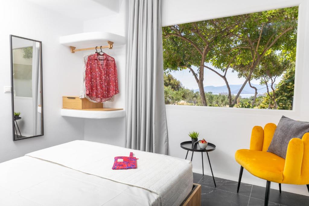a bedroom with a bed and a yellow chair and a window at Vino luxury suites in Agia Anna Naxos