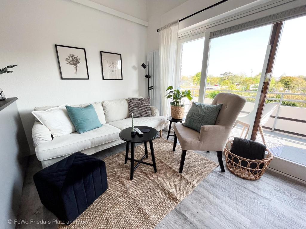 uma sala de estar com um sofá branco e uma mesa em FeWo Frieda's Platz am Meer em Dangast