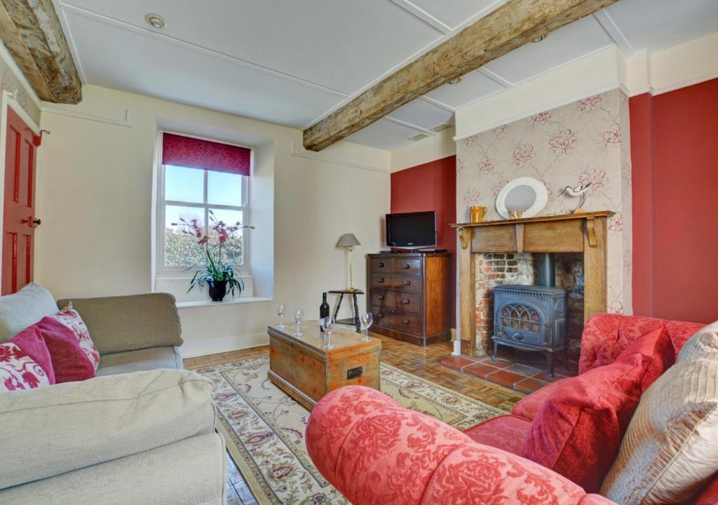 a living room with a couch and a fireplace at Owl Cottage in Little Walsingham