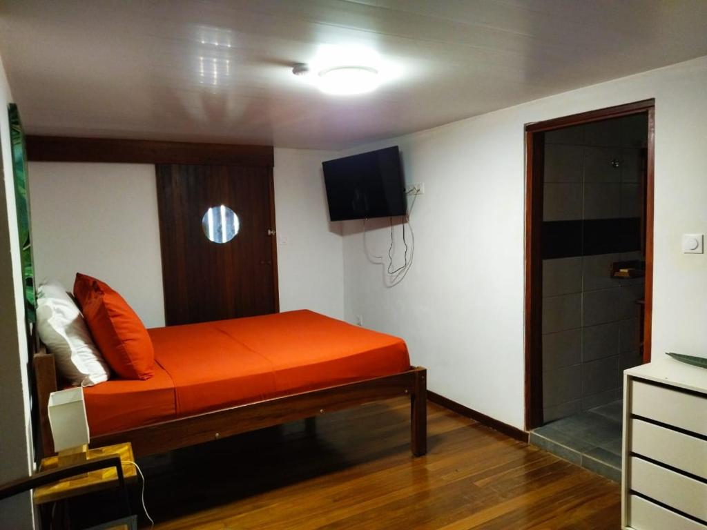 BourdaにあるLE CHALET DOMAINE DU ROCHERのテレビ付きの客室で、オレンジ色のベッド1台を利用できます。