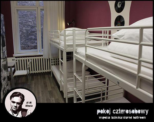 a room with three bunk beds with a picture of a man at La Guitarra Hostel Poznań in Poznań