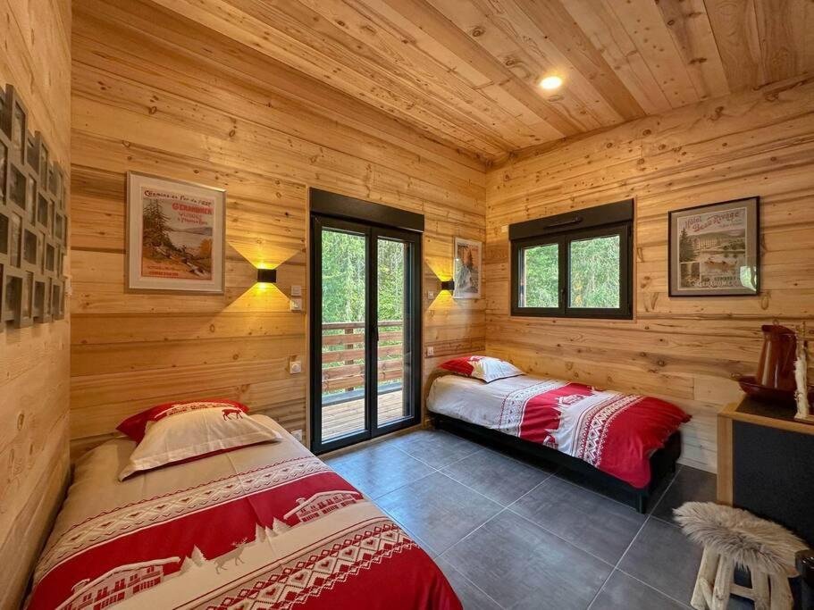 2 camas en una habitación con paredes y ventanas de madera en Le Refuge perché du saut de la bourrique SPA Gérardmer, en Gérardmer