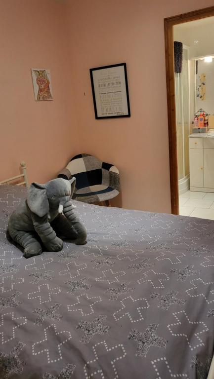 un elefante de peluche sentado en la parte superior de una cama en Chambre 2 personnes, en Guécélard