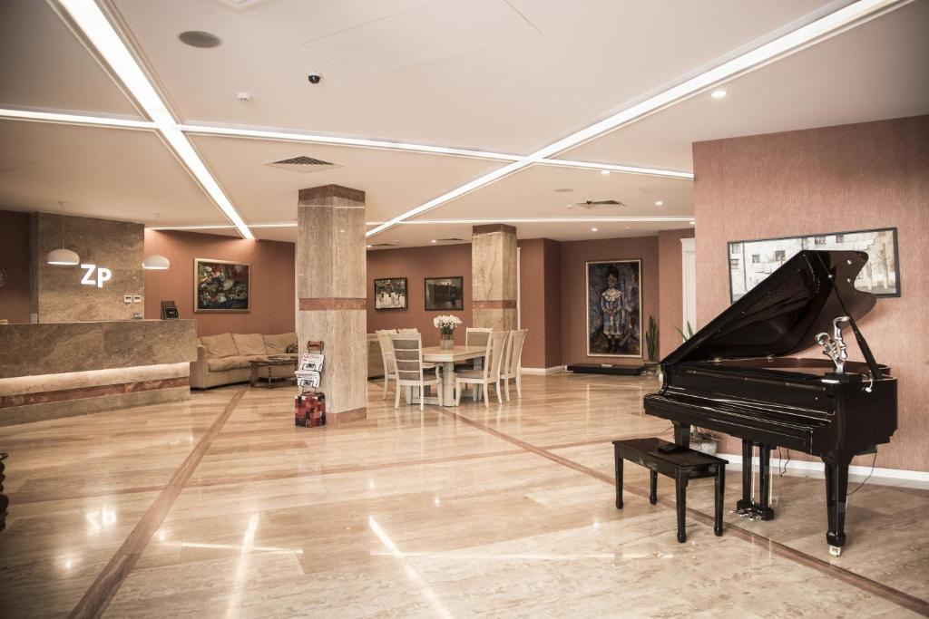 a living room with a piano and a dining room at Hotel ZP Palace in Tbilisi City